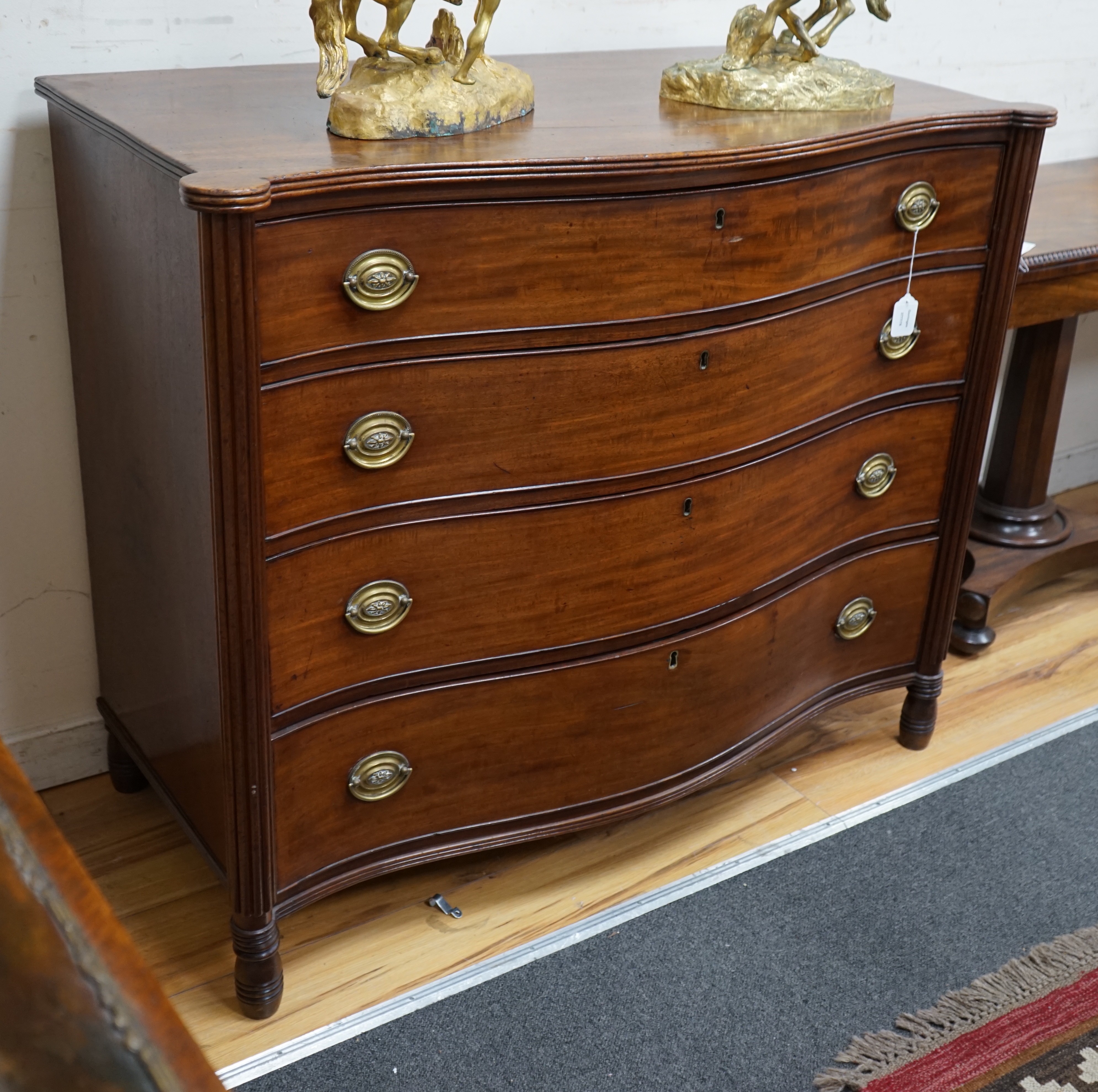 A George III mahogany serpentine chest of four long drawers, width 115cm, depth 58cm, height 97cm